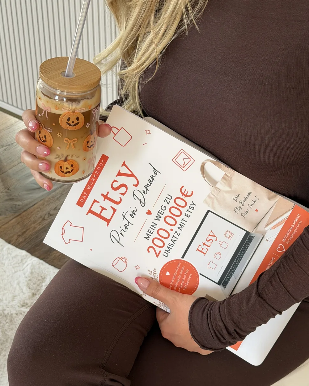 Lotti hält das Etsy-Workbook und ein Glas mit Kürbis-Motiv